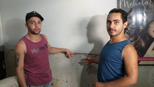 O empresário Diego Fernandes (à esquerda) mostra até onde chegou o nível da água no salão de beleza em Alfredo Chaves por Kaique Dias
