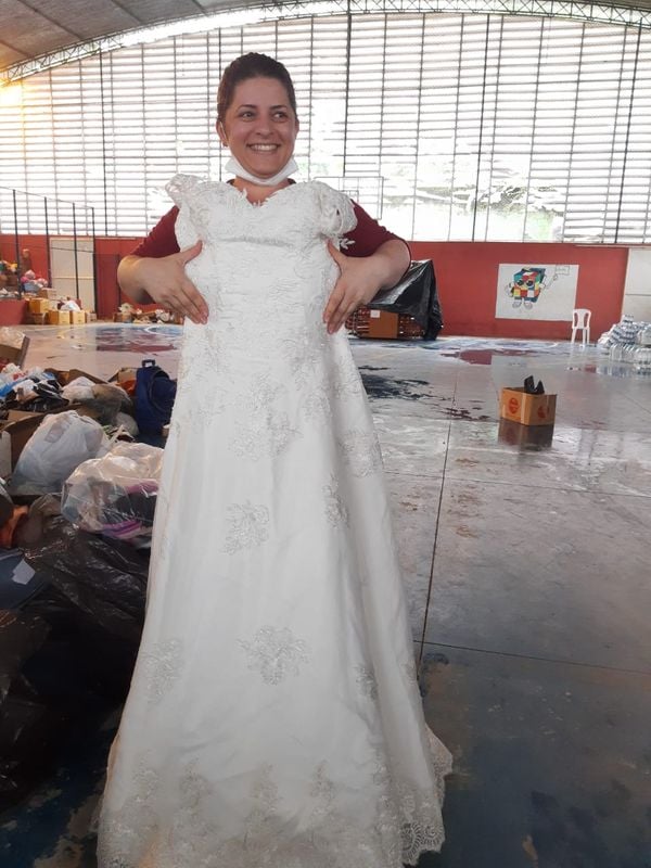 Voluntária mostra o vestido de noiva encontrado em meio às doações em Vargem Alta. Crédito: Luciana Máximo