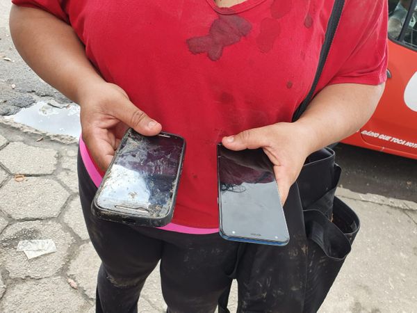 Mulher carrega dois celulares, um deles quebrado, para entregar a ladrão. Crédito: Isaac Ribeiro