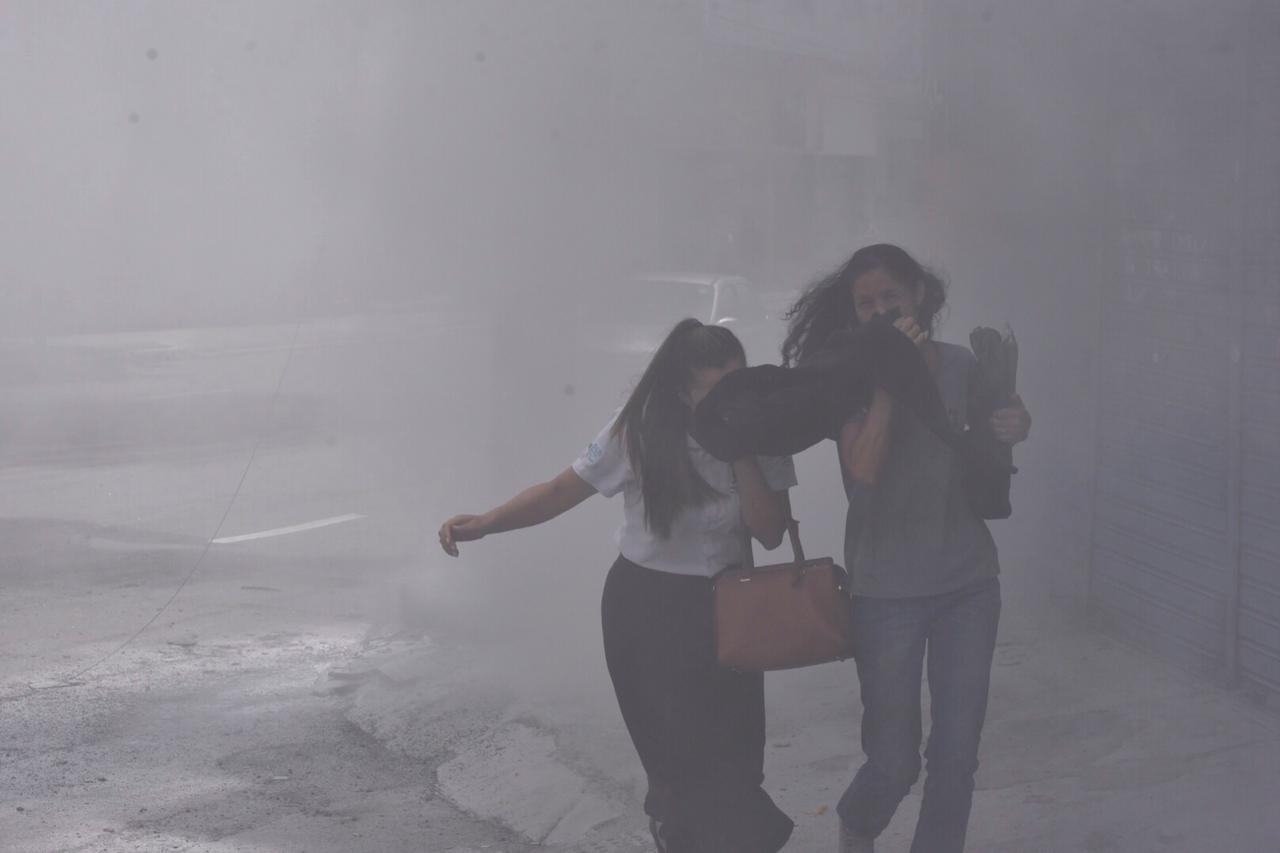 Pessoas se protegem da fumaça do ônibus incendiado na av. Maruípe, próximo a entrada do bairro Tabuazeiro