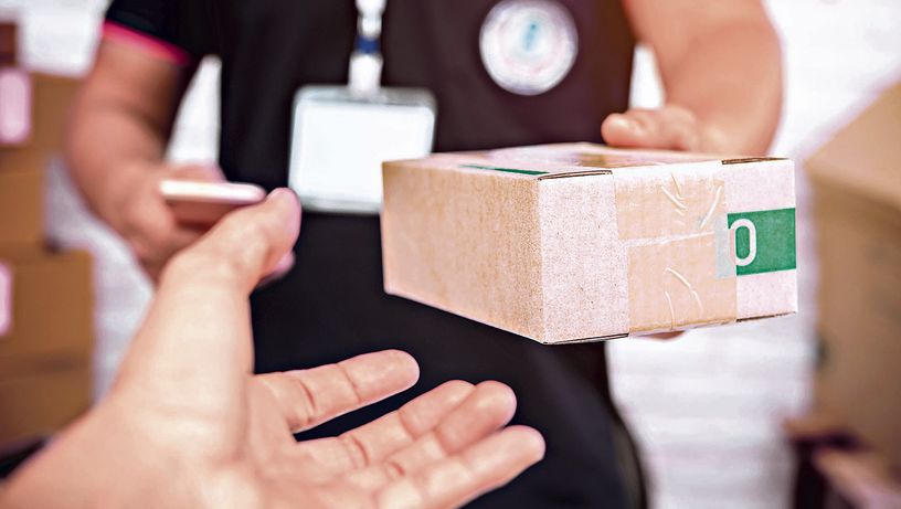delivery man smiling and holding a cardboard box