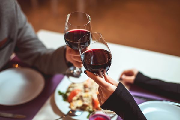 Casal brinca com taças de vinho em restaurante