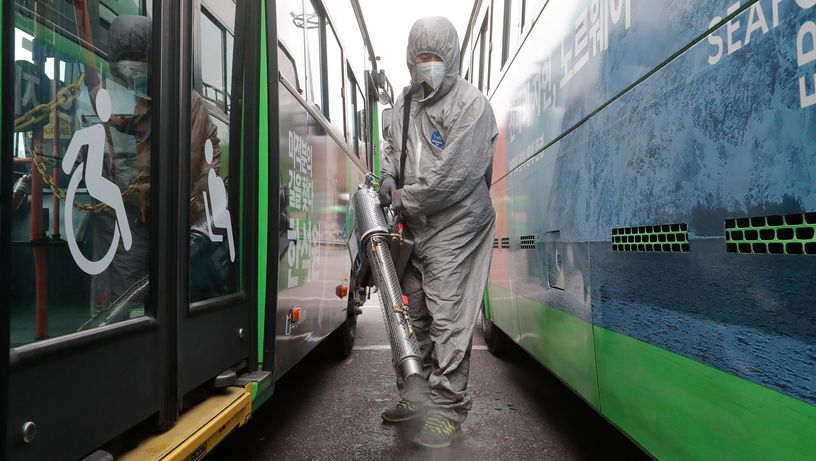 Trabalhadores vestindo roupas de proteção pulverizam desinfetante como precaução contra o coronavírus em uma garagem de ônibus em Seul, na Coreia   do Sul