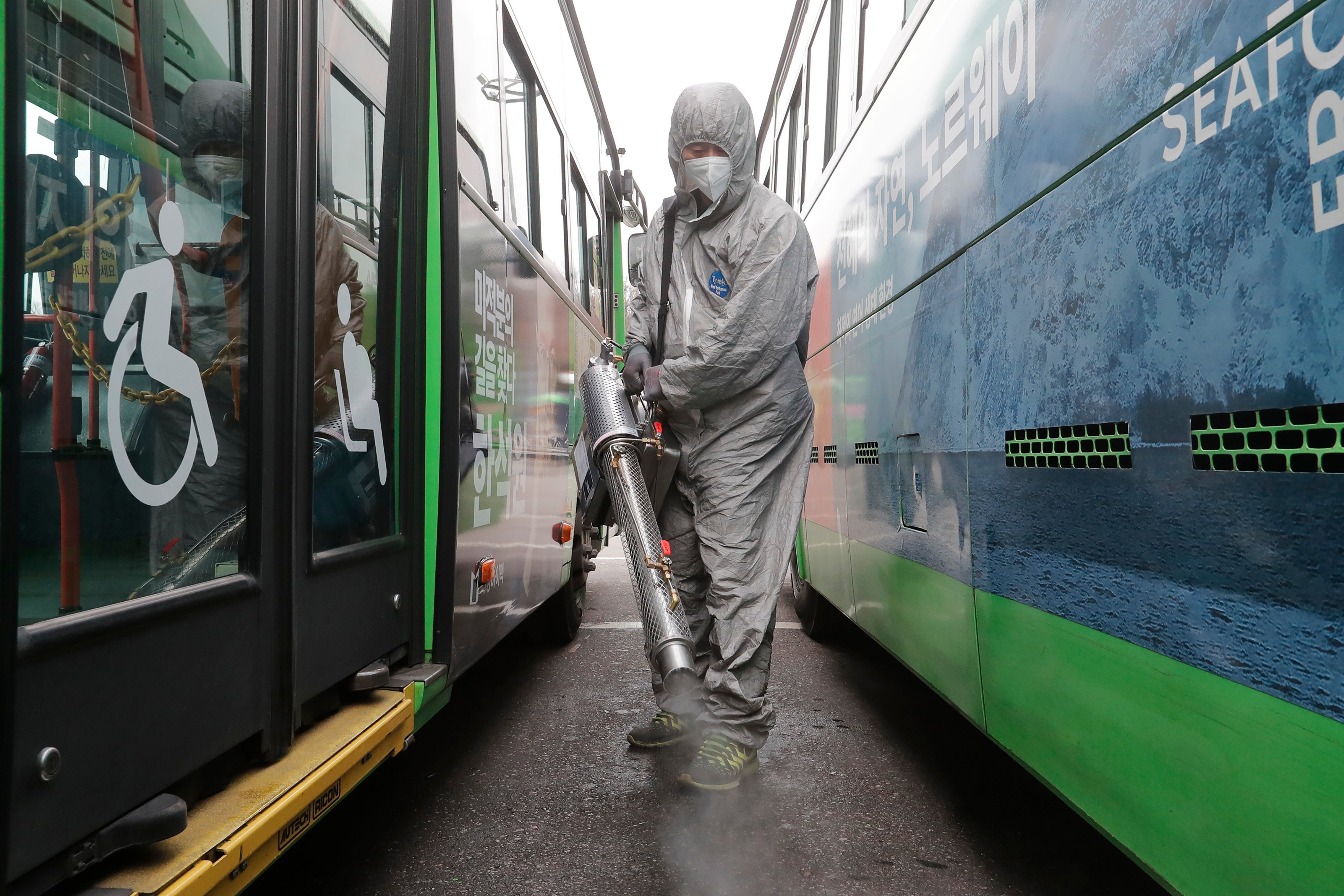 Trabalhadores vestindo roupas de proteção pulverizam desinfetante como precaução contra o coronavírus em uma garagem de ônibus em Seul, na Coreia   do Sul