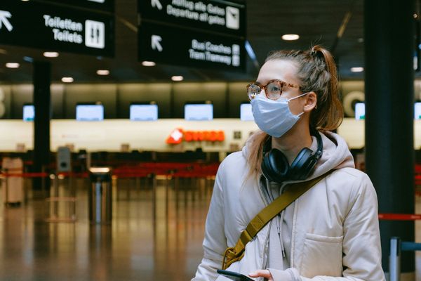 Mulher usa máscara em aeroporto