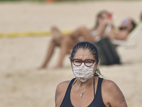 Mulher, na praia da Guarderia,  fazendo caminhada usando máscara por Vitor Jubini