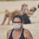 Mulher, na praia da Guarderia,  fazendo caminhada usando máscara