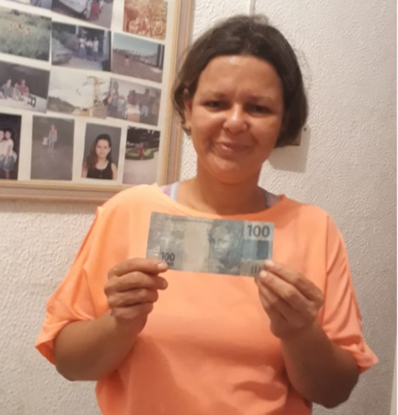 Andreia com a nota de R$ 100 que ganhou de um motorista de carro que passou pela BR 101 e solidarizou com a causa. Crédito: Acervo pessoal