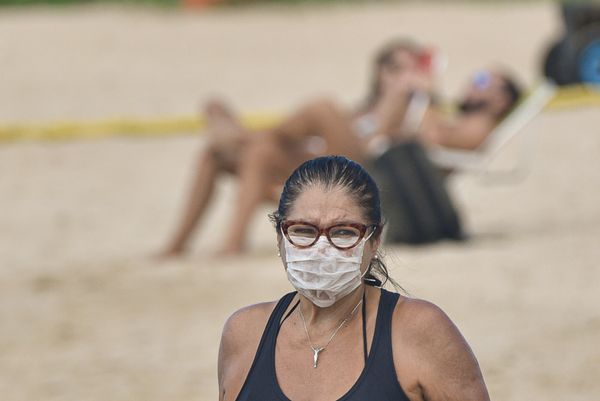 Mulher, na praia da Guarderia,  fazendo caminhada usando máscara por Vitor Jubini