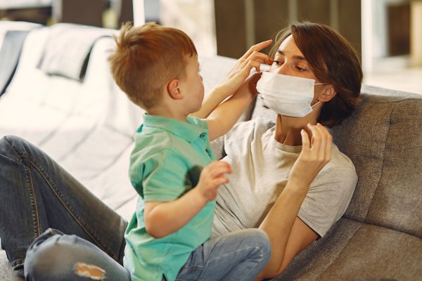 Mulher com máscara brincando com o filho: quarentena na pandemia de coronavírus 