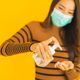 Mulher de máscara passando álcool em gel nas mãos: prevenção ao coronavírus