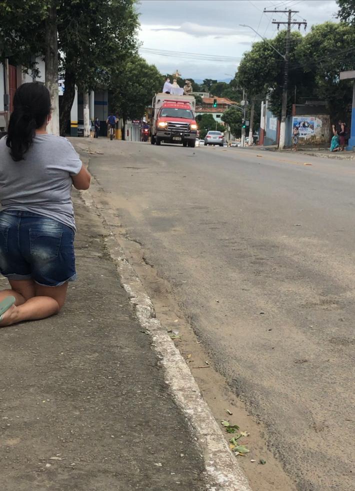 Ajoelhada, mulher aguarda pela passagem da procissão em Aracruz