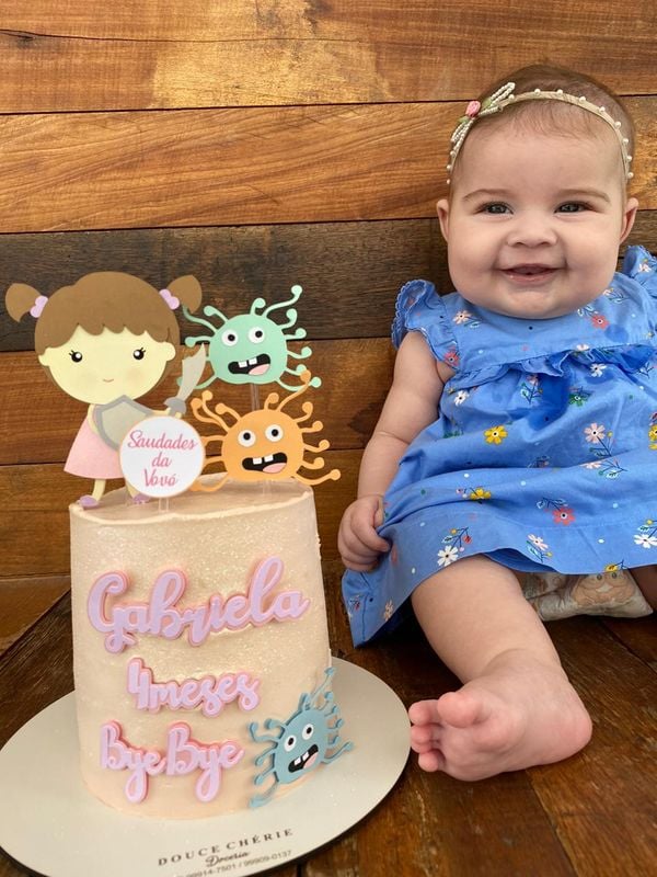 Aos quatro meses, a pequena Gabriela ao lado do bolo que diz "bye bye" para o coronavírus por Acervo pessoal