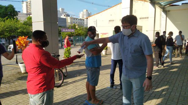 Servidores distribuem máscaras e higienizam mãos de pessoas em filas formadas nas agências da Caixa em Vila Velha