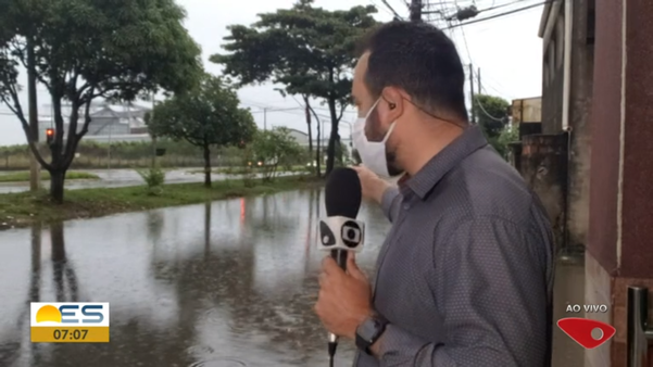 O repórter Aurélio de Freitas, da TV Gazeta, mostra trecho alagado na rua Buenos Aires, no bairro Araçás, em Vila Velha na manhã desta segunda-feira (25)