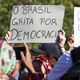 Manifestante com cartaz sobre democracia no Brasil, durante ato no Largo da Batata, em São Paulo, neste domingo (7)