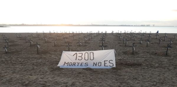 Cruzes e faixa colocadas na areia da Praia de Camburi neste domingo (21) fazem menção a mortos pelo novo coronavírus no ES por Plenária contra a Covid-19