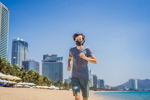 Homem correndo na praia de máscara