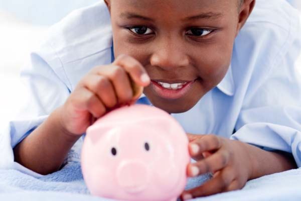 Menino colocando dinheiro no cofre: educação financeira