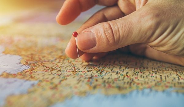Pessoa marca em um mapa local para onde vai viajar