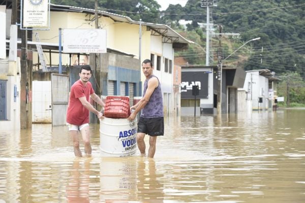 Moradores se arriscam em rua alagada para salvar pertences em Iconha