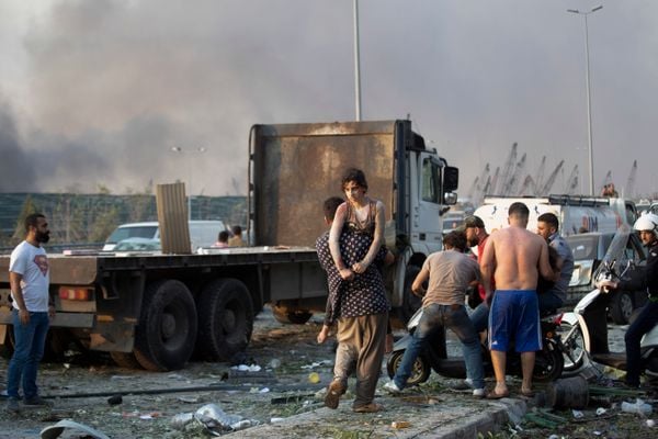 Pessoas, muitas delas feridas, circulam pelas ruas cobertas de escombros após uma forte explosão na área portuária de Beirute, no Líbano
