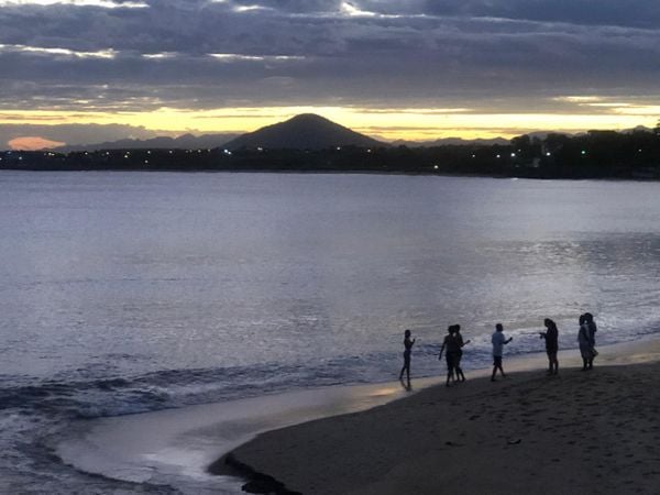 A imagem mostra parte da praia de Meaípe, em Guarapari, com algumas pessoas que tentaram auxiliar a baleia em pé na areia.