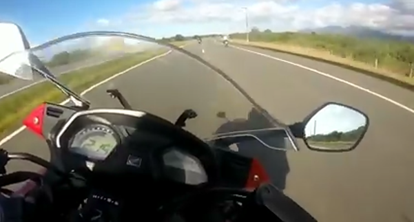 A imagem mostra o painel de uma motocicleta com o velocímetro atingindo 215 km/h em uma estrada.