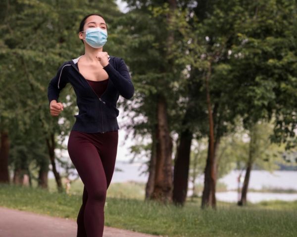 Mulher correndo com máscara de proteção facial