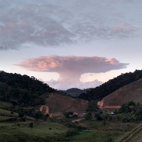 A imagem mostra uma grande nuvem em formato de explosão com um vale gramado