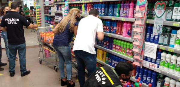 A imagem mostra fiscais do Procon analisando produtos em prateleiras de um supermercado
