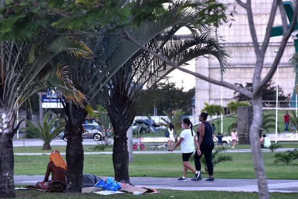 Duas mulheres fazem caminhada na Praça do Papa e um homem em situação de rua descansa na grama ao lado por Fernando Madeira