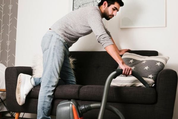 Homem limpando casa com aspirador