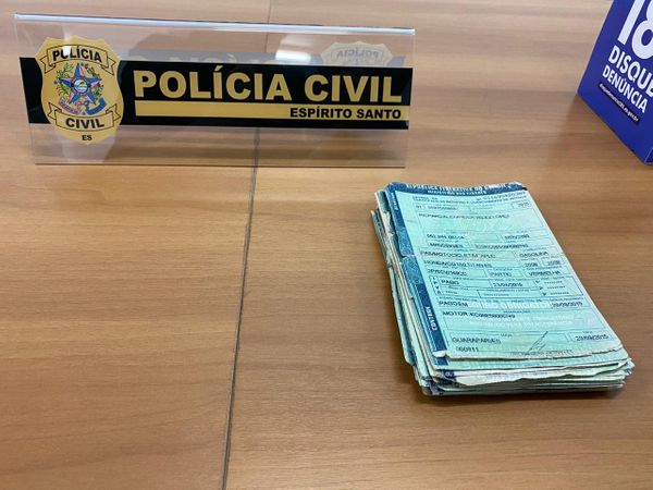 Pilha de documentos de veículos e um distintivo da Polícia Civil
