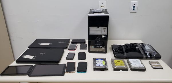 A imagem mostra equipamentos eletrônicos apreendidos pela Polícia Civil dispostos em cima de uma mesa
