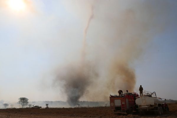 Bombeiros do Estado de Mato Grosso abastecem seu caminhão com água enquanto se preparam para apagar um incêndio em frente a um funil de fumaça, em uma fazenda no Pantanal por  Amanda Perobelli/REUTERS/Folhapress