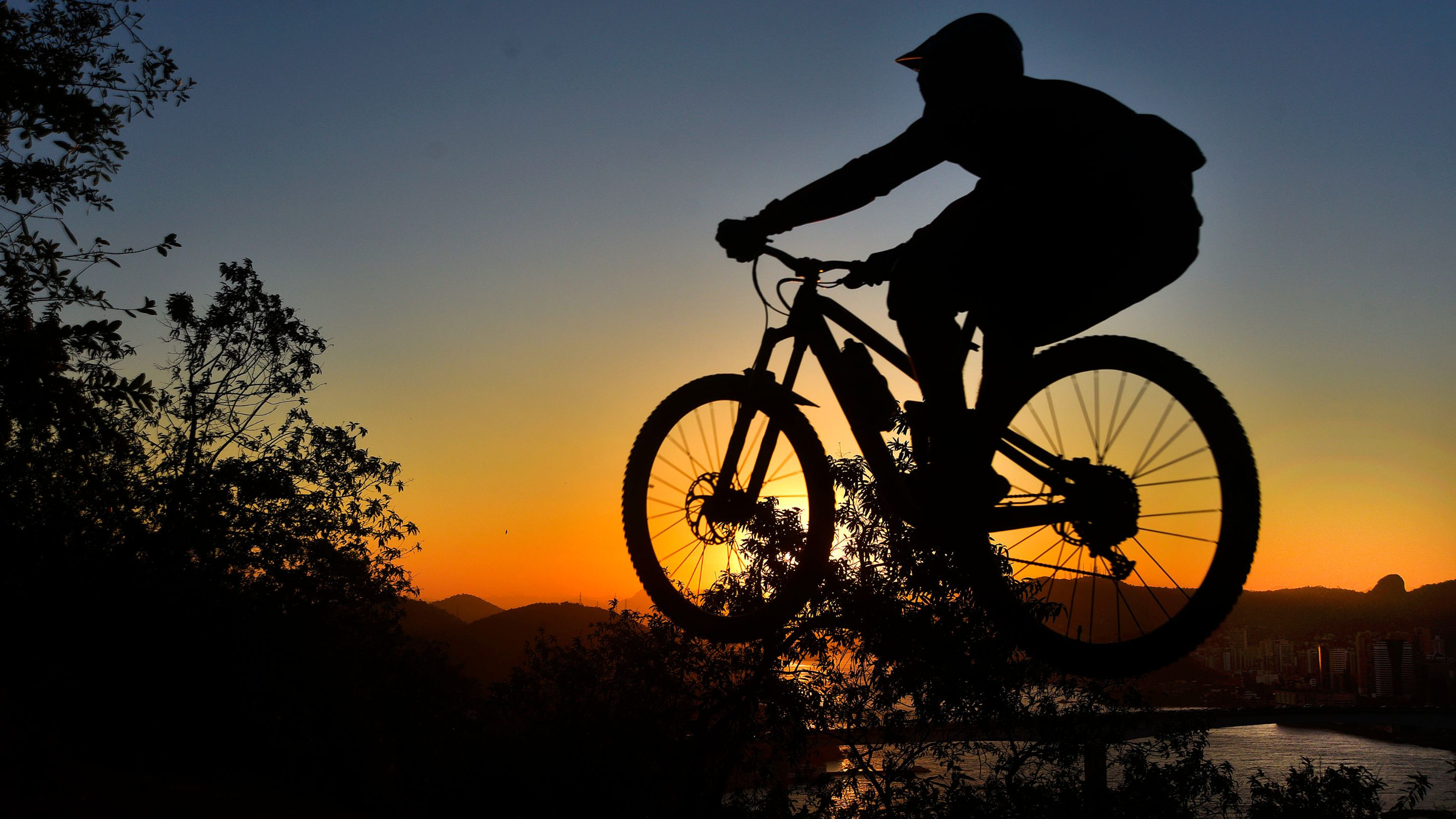 Ciclista salta rampa diante do pôr do sol na trilha do Morro do Moreno, em Vila Velha, ES