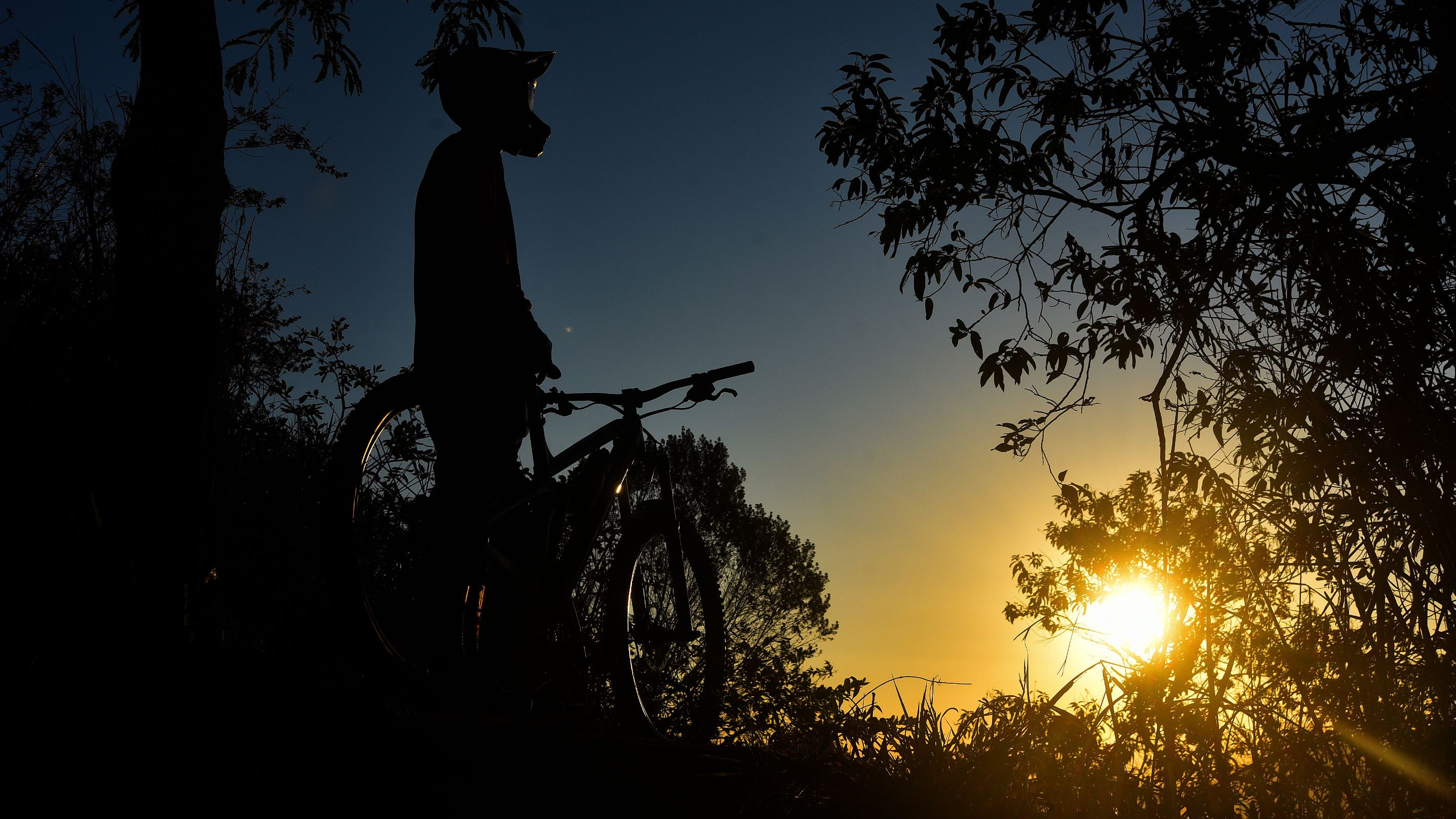 Ciclista contempla o pôr do sol na trilha do Morro do Moreno, em Vila Velha, ES