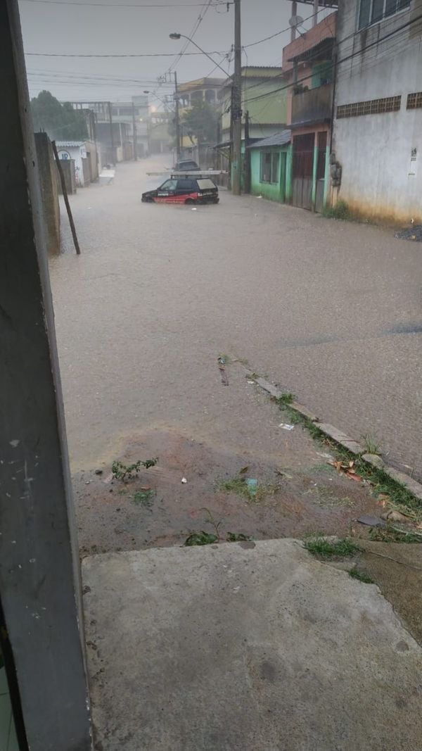 Rua Emílio Chagas, no bairro Vila Independência, em Cariacica, completamente alagada, com um carro com água até os pneus no meio da rua