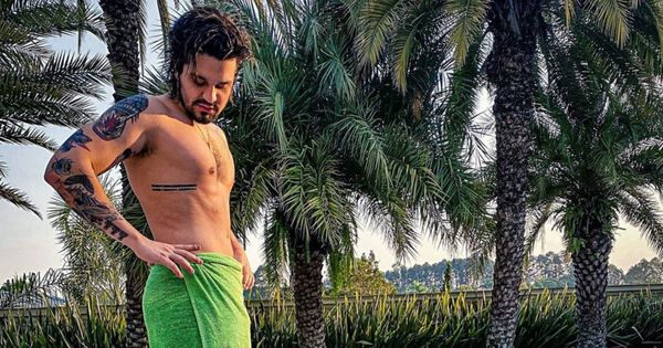 O cantor Luan Santana posa em área de piscina só com toalha pendurada na cintura