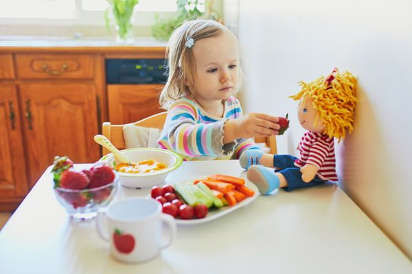 Criança brincando de boneca, de dar comida pra boneca