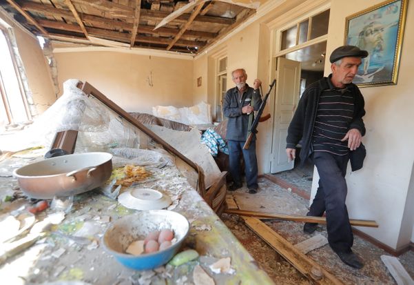  Residentes locais mostram uma casa danificada após um recente bombardeio