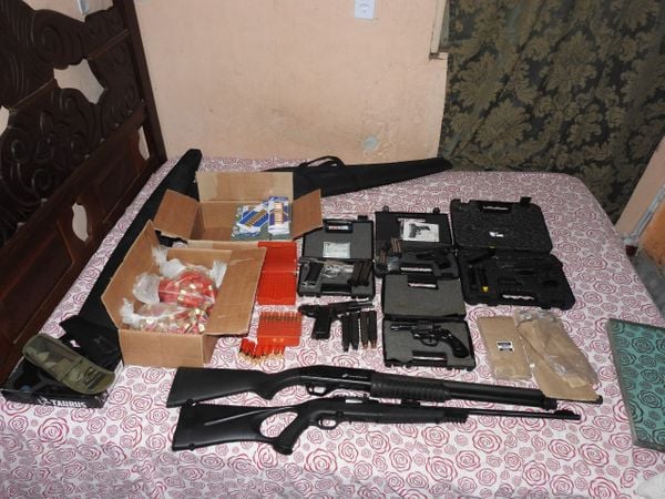Armas de vários tipos e munições em cima de uma cama