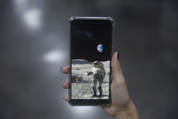Mulher segurando celular com a imagem feita da lua
