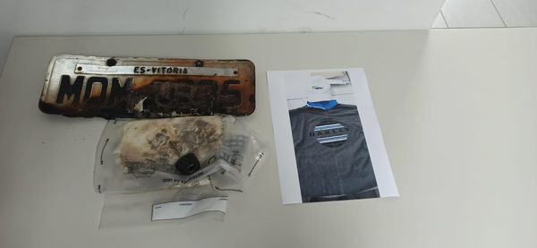 Placa do carro usado pelos criminosos e que foi queimado; a camisa era usada pelo menor envolvido