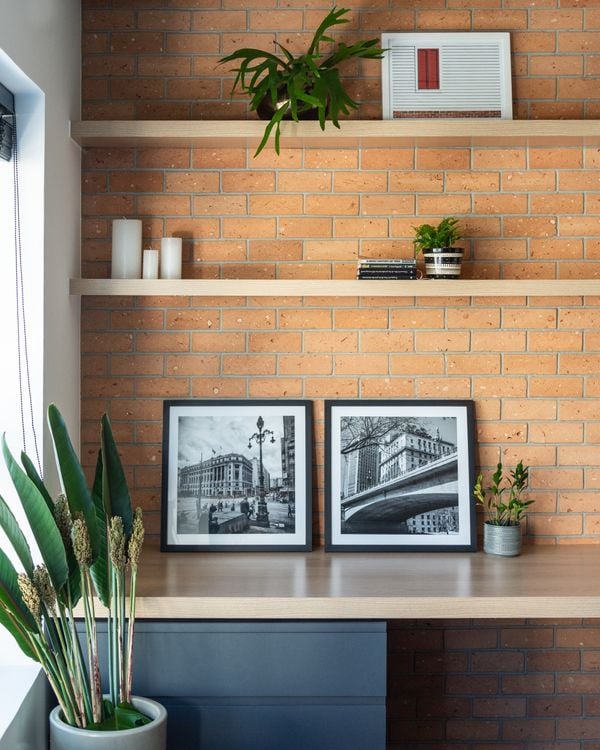 Nesse home office, a arquiteta Júlia Guadix colocou plantas, quadros e velas para compor um bonito fundo com a parede de tijolinhos | Projeto: Liv’n Arquitetura |