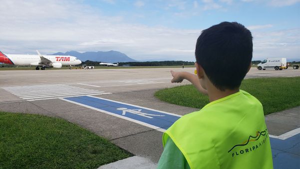 Menino observa avião na pista durante tour guiado no Floripa Airport
