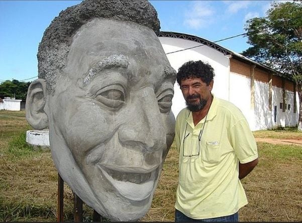 Genésio Gomes de Moura, em 2008, ao lado de uma de suas criações, durante a construção da estátua em homenagem a Pelé, em Três Corações/MG