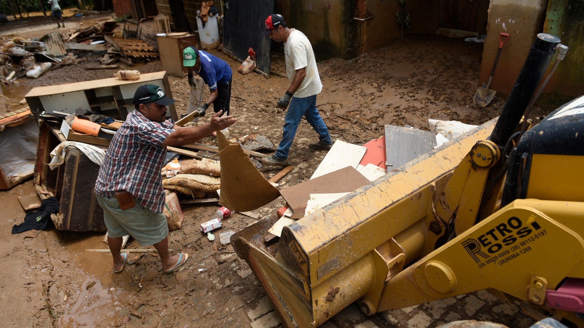 Um trator ajuda moradores a retirar os restos de móveis da rua. Bairro Garage