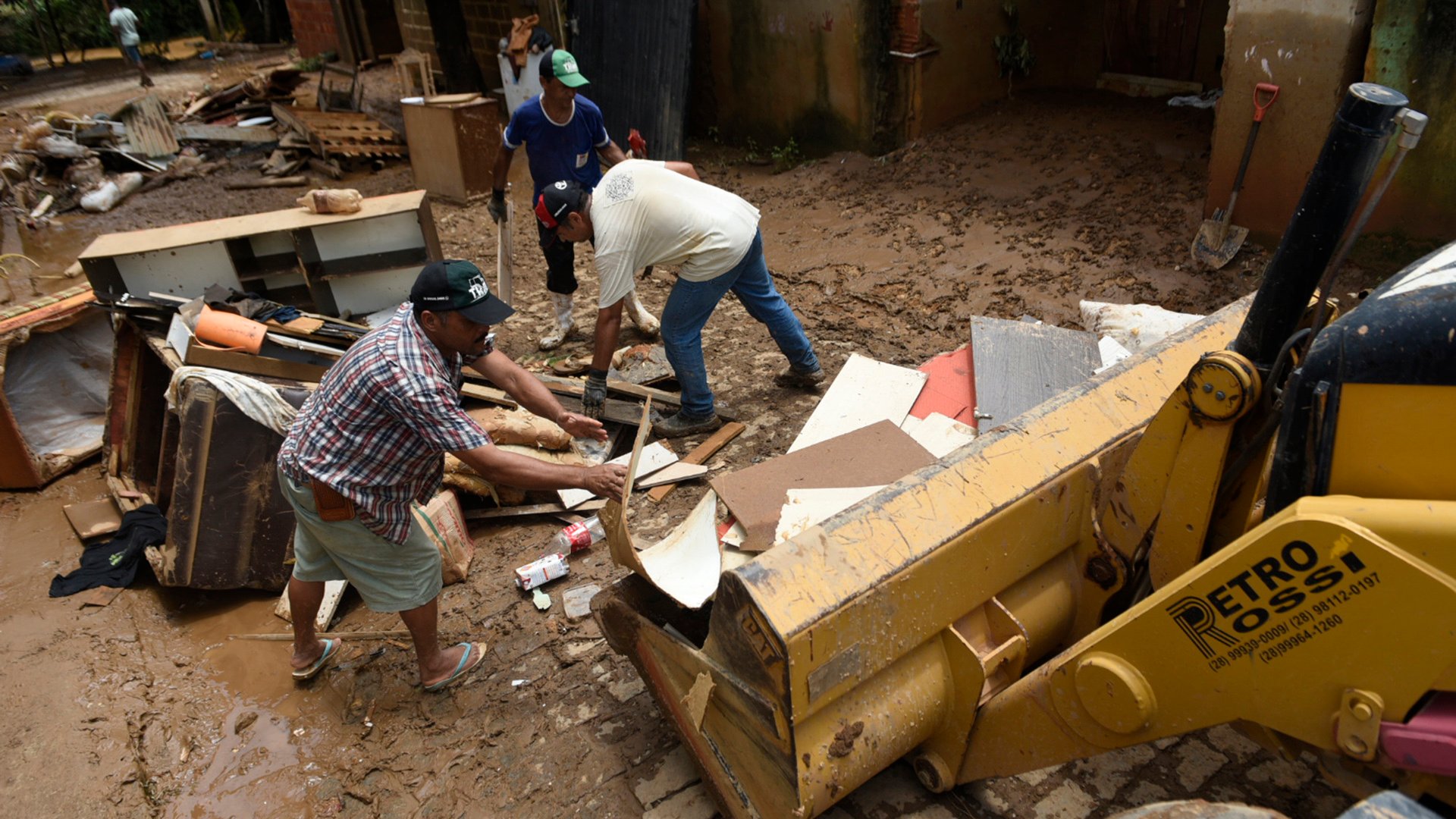 Um trator ajuda moradores a retirar os restos de móveis da rua. Bairro Garage